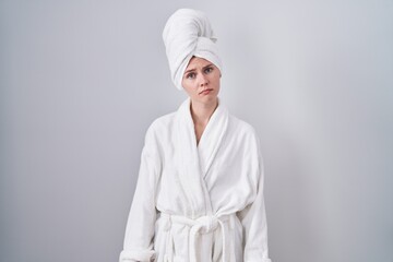 Blonde caucasian woman wearing bathrobe looking sleepy and tired, exhausted for fatigue and hangover, lazy eyes in the morning.