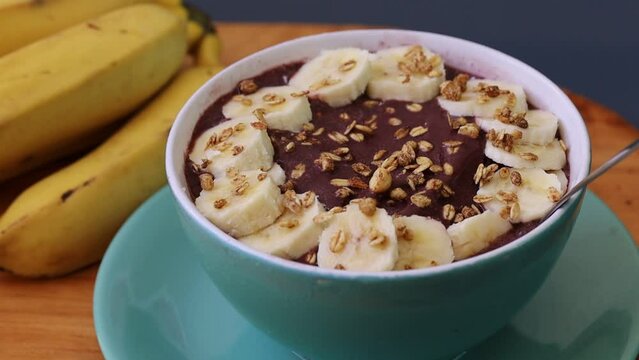 A&ccedil;a&iacute; congelado na tigela com banana e granola sobre uma t&aacute;bua de madeira. Comida brasileira, sobremesa
