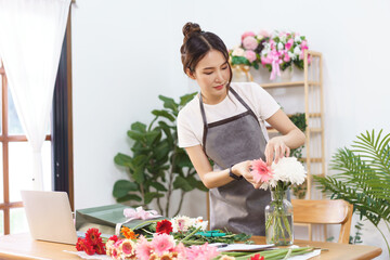 Florist concept, Female florist arranging pink gerbera and chrysanthemum in vase at flower shop