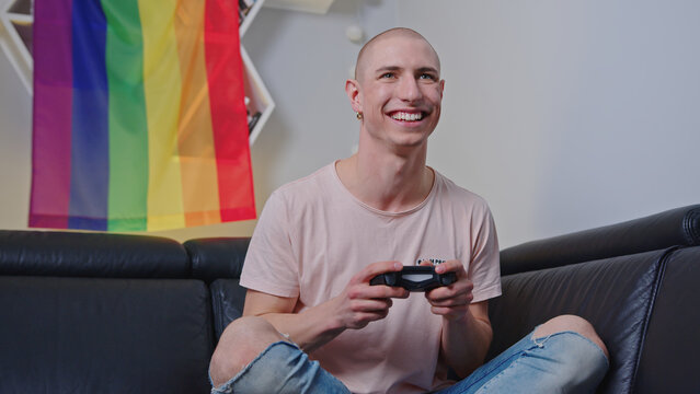 Smiling queer man playing video games with a consol indoor. High quality photo