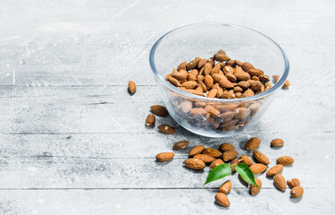 Almonds in a glass bowl with leaves .