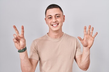Fototapeta premium Young man standing over isolated background showing and pointing up with fingers number seven while smiling confident and happy.