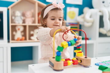 Adorable blonde toddler playing with toys standing at kindergarten