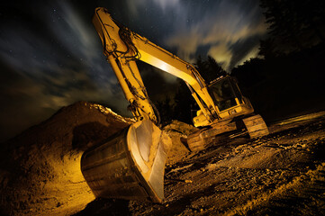 Excavator at night, dramatic lighting and composition, with clouds and stars in the sky in background