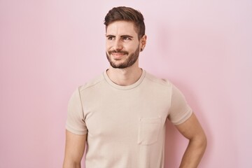 Hispanic man with beard standing over pink background smiling looking to the side and staring away thinking.