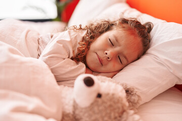 Adorable blonde toddler lying on bed sleeping with teddy bear at bedroom
