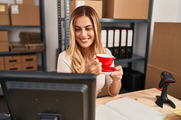 Young blonde woman ecommerce business worker drinking coffee at office