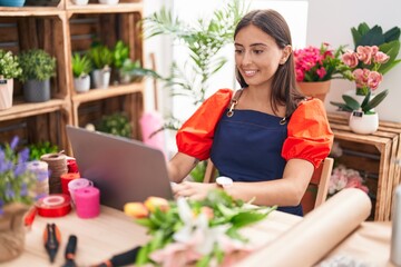 Obraz na płótnie Canvas Young beautiful hispanic woman florist smiling confident using laptop at florist