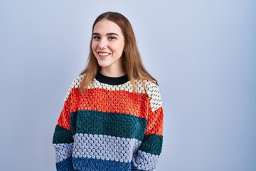 Young hispanic girl standing over blue background winking looking at the camera with sexy...