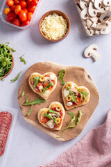 Heart shape mini pizzas on wooden board for Valentines day holiday, top view