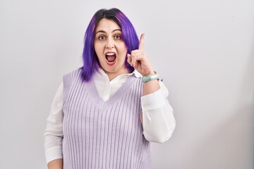 Plus size woman wit purple hair standing over white background pointing finger up with successful idea. exited and happy. number one.