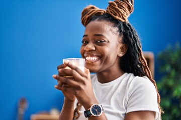 African american woman smelling aromatic candle standing at home