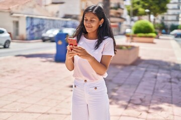 Young beautiful hispanic woman smiling confident using smartphone at street