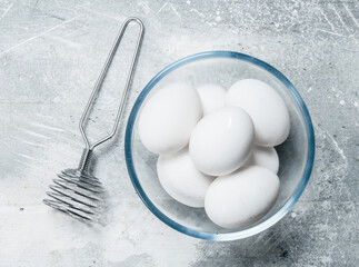 Eggs in a glass bowl with a whisk.