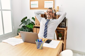 Middle age grey-haired man business worker relaxed with hands on head at office