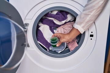 Middle age woman pouring detergent on washing machine at laundry room