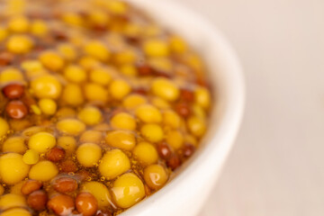 French mustard in a white saucer on a wooden table, macro.