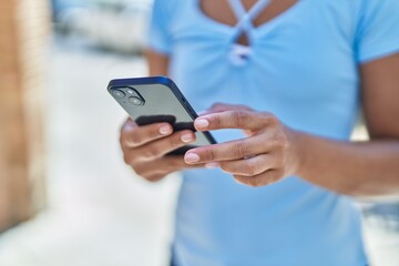 Young beautiful hispanic woman using smartphone at street
