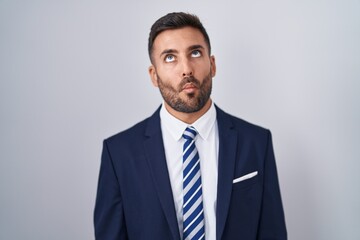 Handsome hispanic man wearing suit and tie making fish face with lips, crazy and comical gesture. funny expression.