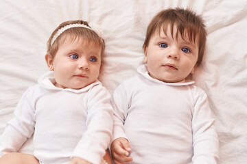 Two adorable babies lying on bed at bedroom