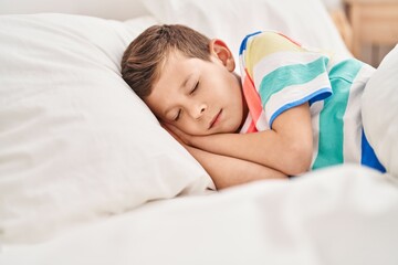 Blond child hugging teddy bear sleeping on bed at bedroom