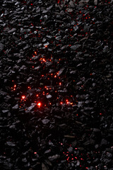 Texture of black coal stones with red rays of flame in the middle.