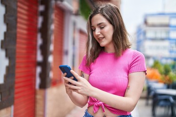 Young woman smiling confident using smartphone at street