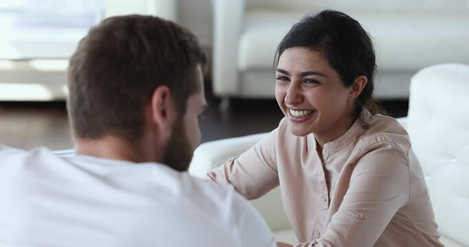 Pretty Indian girl talks to boyfriend sit together in cozy cafe, drink tea, having pleasant nice conversation, laughing feel happy spend free time with best guy friend, close up. Relations, friendship