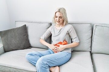 Obraz premium Young caucasian woman using hot water bag for period pain at home