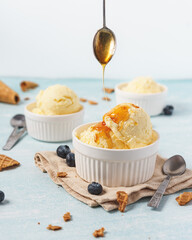 Vanilla ice cream dripping with honey decorate with blueberries and waffle cones on the blue background