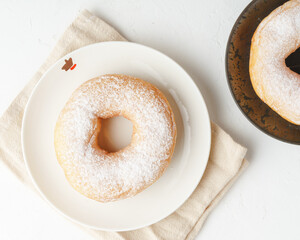 donuts on a white plate and black plate and white backdrop