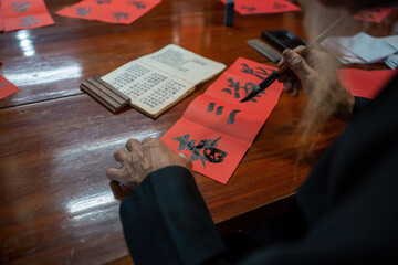Old Vietnamese scholar writes calligraphy at lunar new year. Calligraphy festival is a popular tradition during Tet holiday. Culture of Vietnamese Tet in springtime
