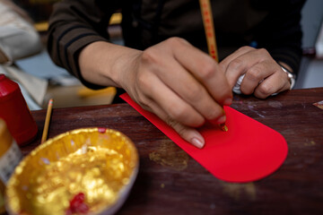 Selective focus of hand of Vietnamese scholar writes calligraphy at lunar new year. Calligraphy festival is a popular tradition during Tet holiday. Text in photo mean Happy New Year and Peace.