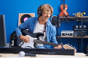 Young man artist singing song playing electrical guitar at music studio