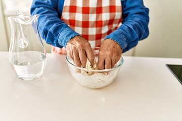 Senior man cooking dough at kitchen