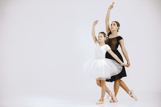 Mother and daughter ballet dancers against white background