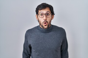 Handsome latin man standing over isolated background afraid and shocked with surprise and amazed expression, fear and excited face.