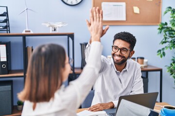 Man and woman business workers high five with hands raised up at office