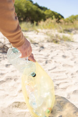 Close up man hand pick up the plastic bottle on the beach. Volunteer clean the trash on the beach .