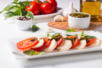 Close-up photo of caprese salad with ripe tomatoes, basil, buffalo mozzarella cheese. Italian and Mediterranean food concept. Fresh and healthy organic meal. Starter and antipasti. 