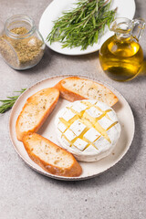 Baked camembert soft cheese. Grilled brie with toasts and rosemary. 
