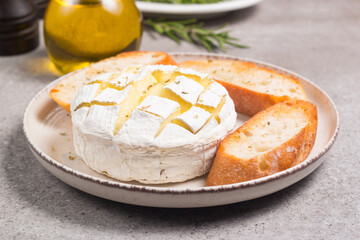 Baked camembert soft cheese. Grilled brie with toasts and rosemary. 