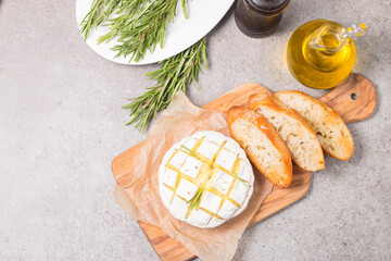 Baked camembert soft cheese. Grilled brie with toasts and rosemary. 