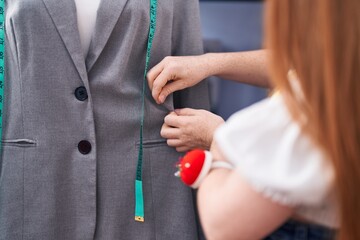 Young redhead woman tailor measuring t shirt at clothing factory