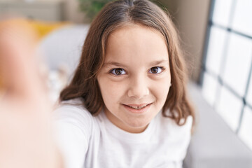 Adorable hispanic girl make selfie by camera sitting on sofa at home