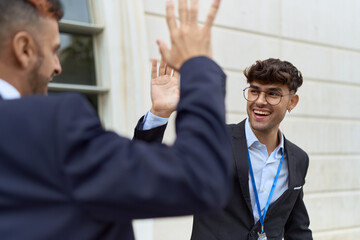 Two hispanic men business workers high five with hands raised up at street