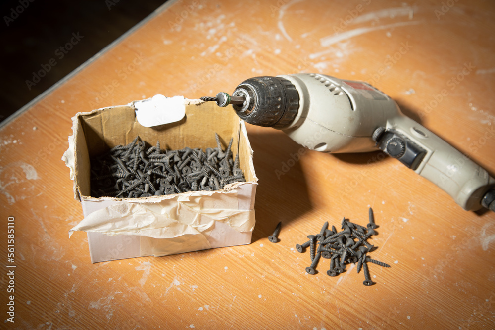 Wall mural drill with screws on the table.