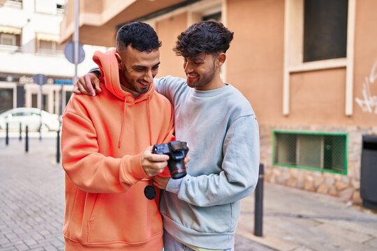 Two man couple using professional camera at street