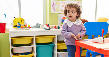 Adorable hispanic girl playing with money standing at kindergarten