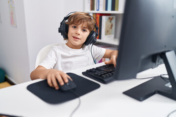 Fototapeta na wymiar Adorable caucasian boy student using computer sitting on table at classroom